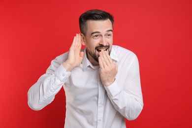 Photo of Man showing hand to ear gesture on red background