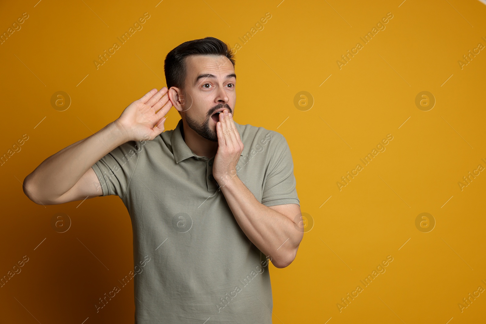 Photo of Man showing hand to ear gesture on orange background, space for text