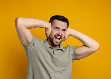 Photo of Man covering his ears on orange background