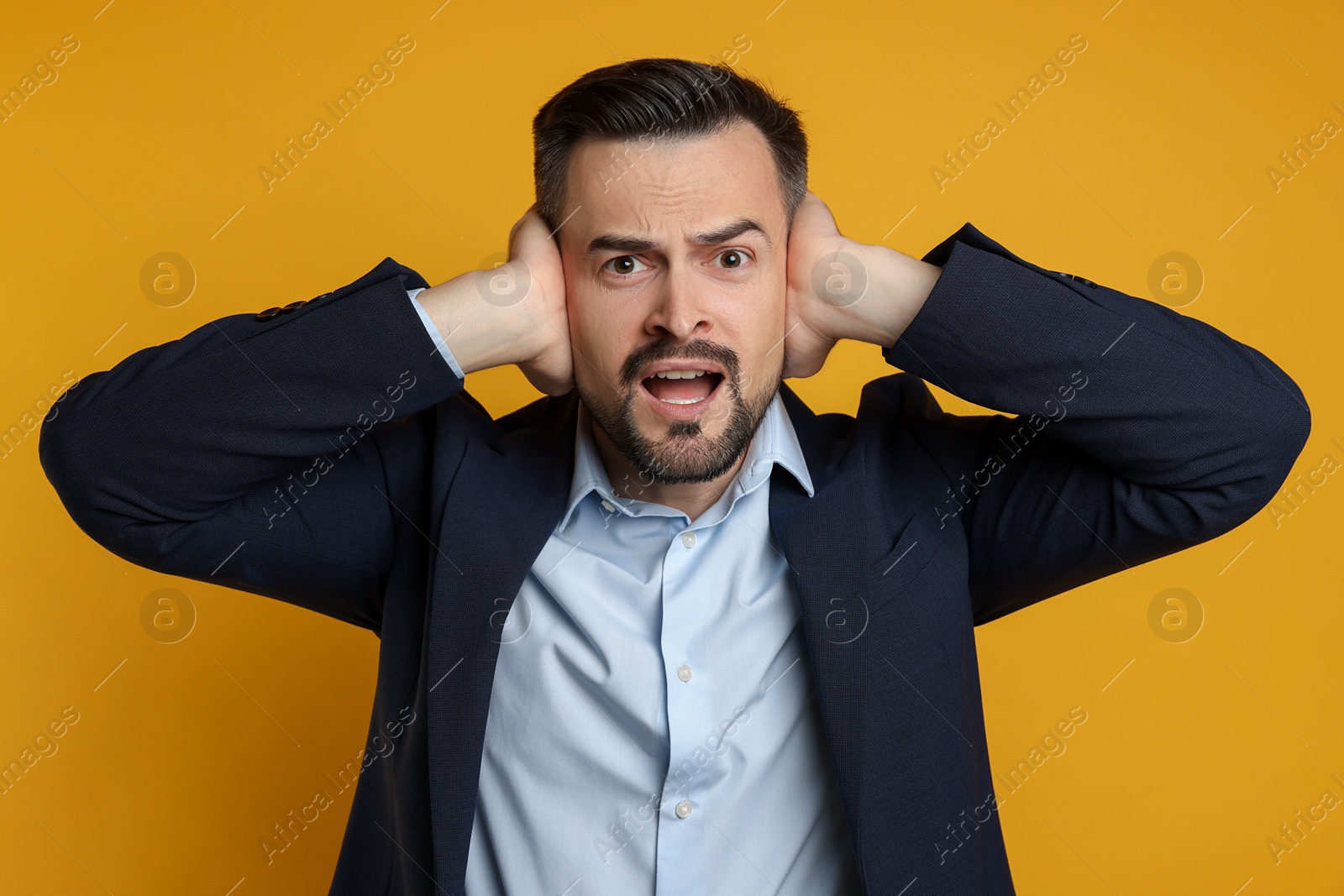 Photo of Man covering his ears on orange background