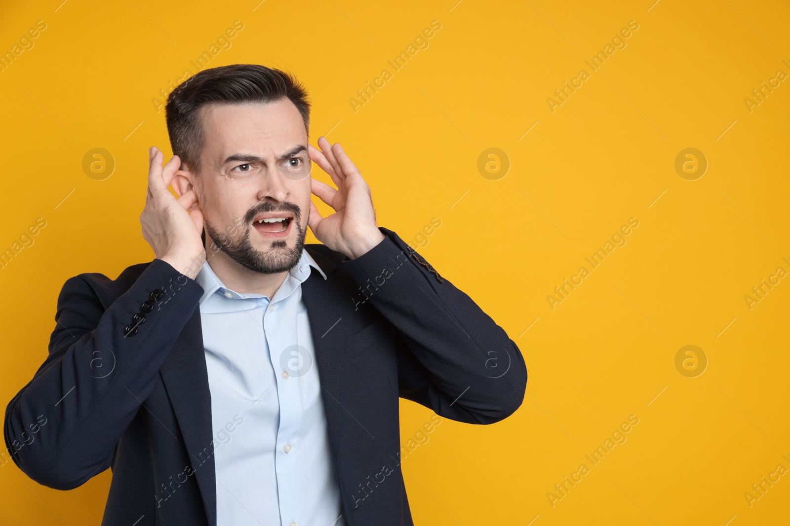 Photo of Man covering his ears with fingers on orange background, space for text