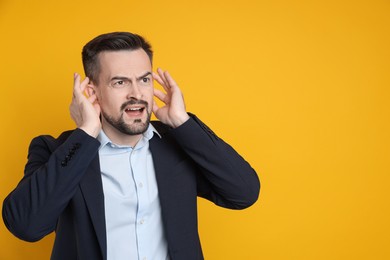 Photo of Man covering his ears with fingers on orange background, space for text