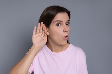 Woman showing hand to ear gesture on grey background