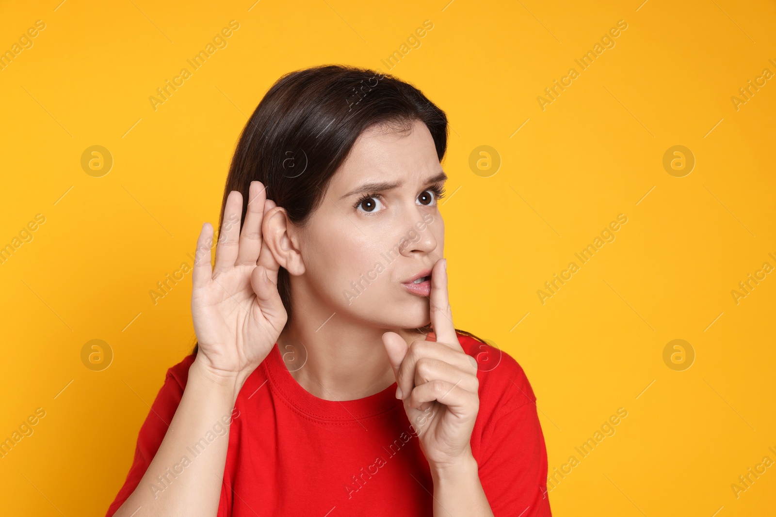 Photo of Woman showing hand to ear gesture on orange background