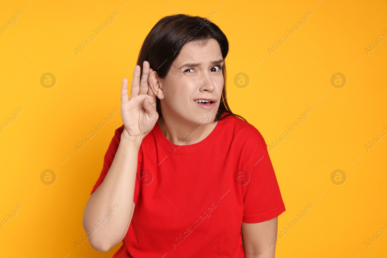 Photo of Woman showing hand to ear gesture on orange background