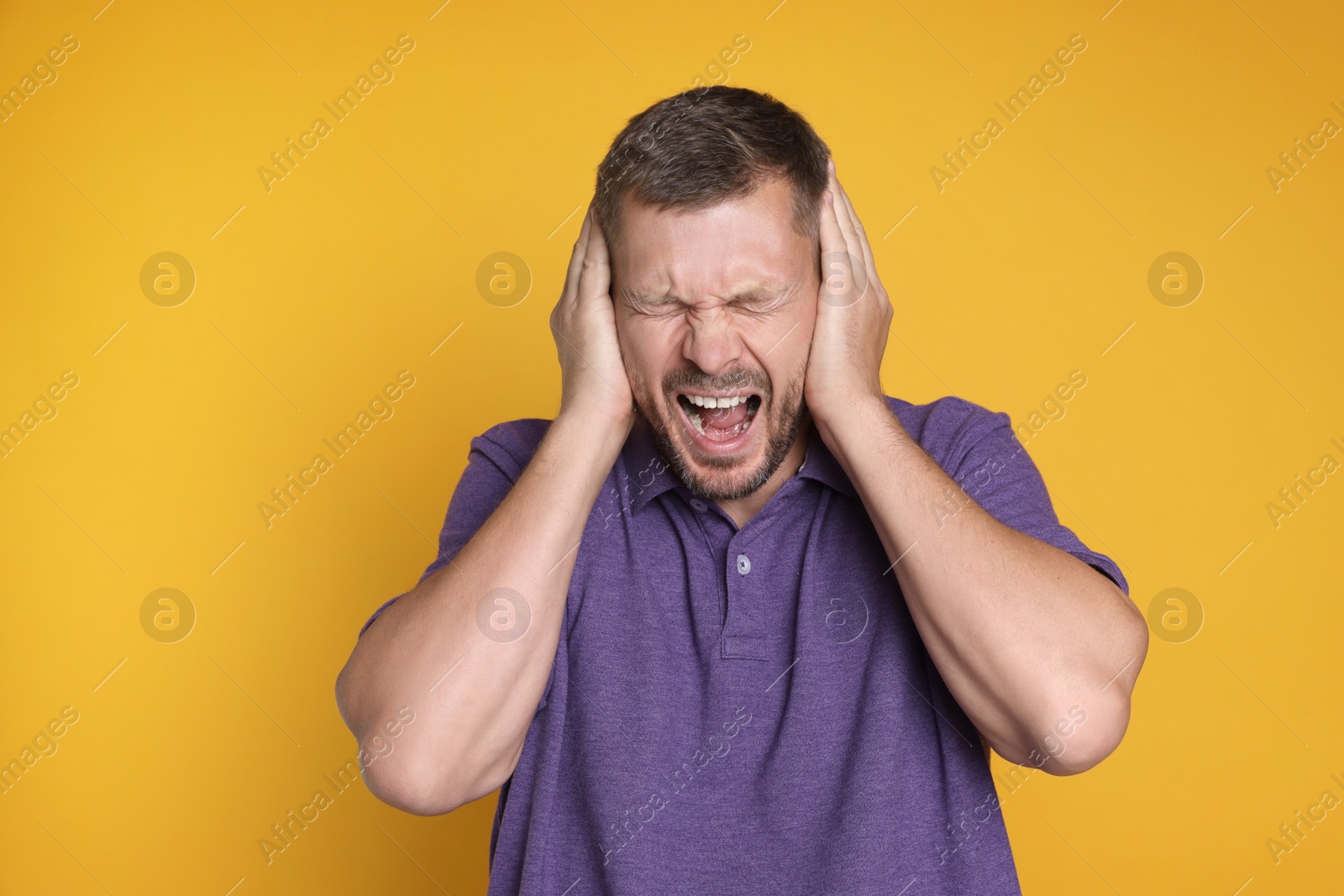 Photo of Man covering his ears on orange background