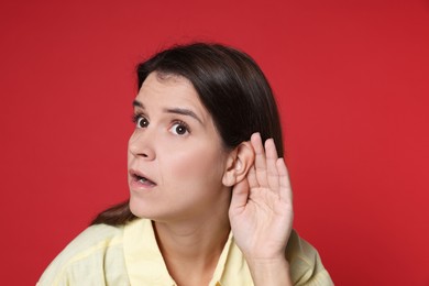 Photo of Woman showing hand to ear gesture on red background