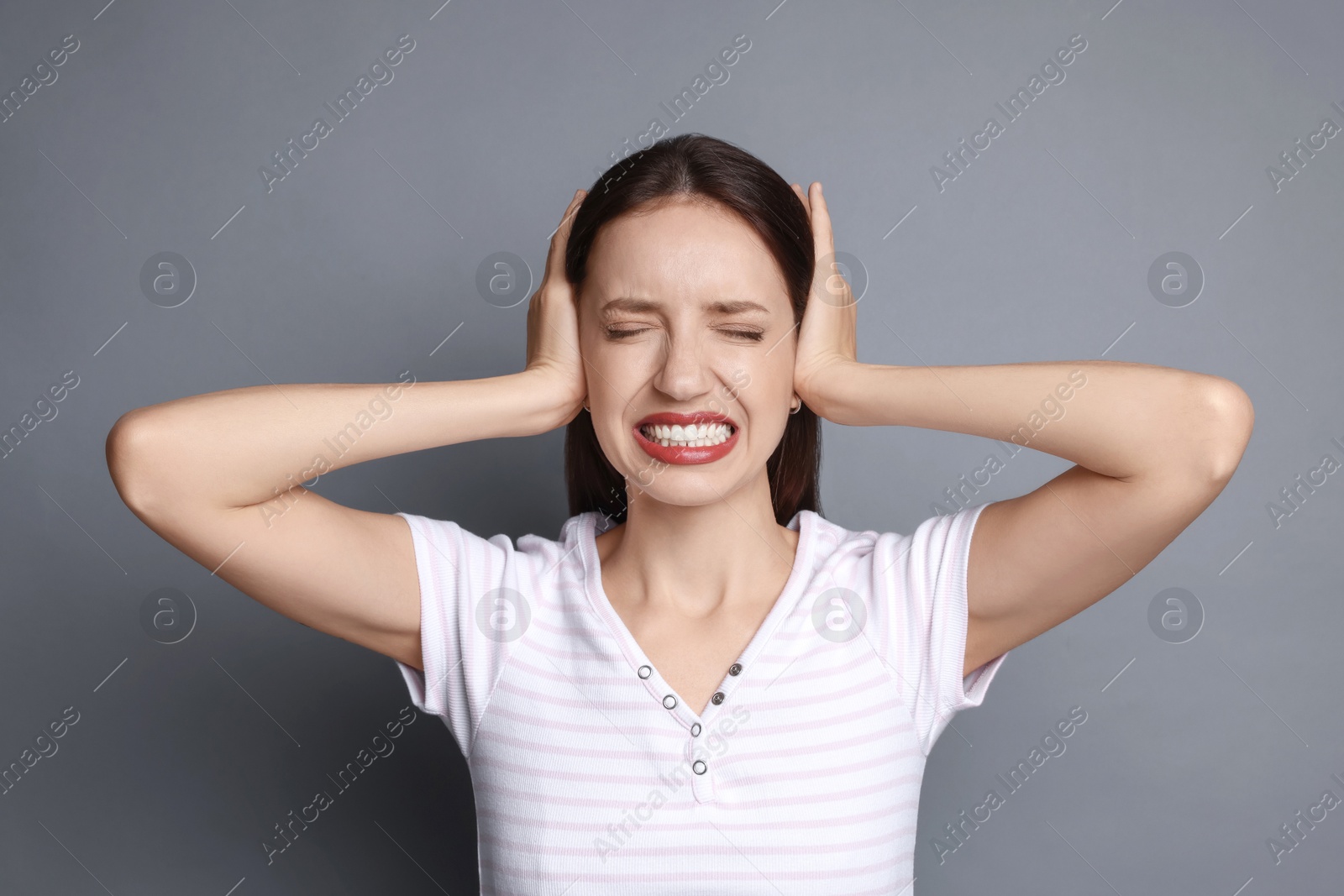 Photo of Woman covering her ears on grey background