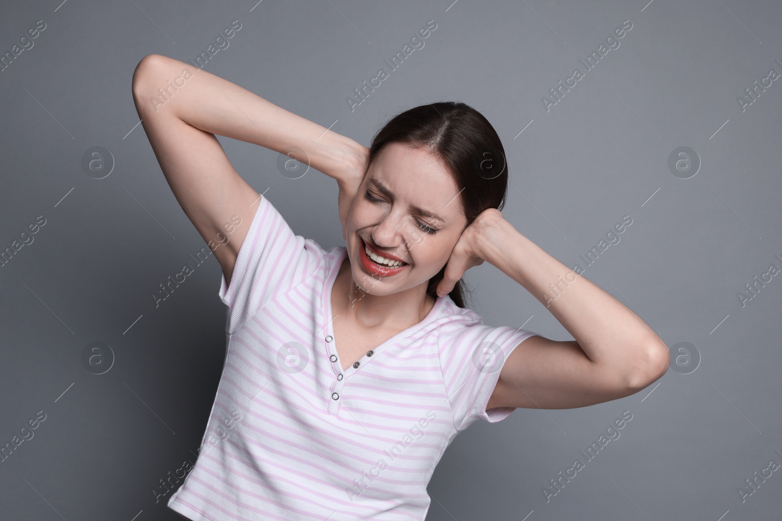 Photo of Woman covering her ears on grey background