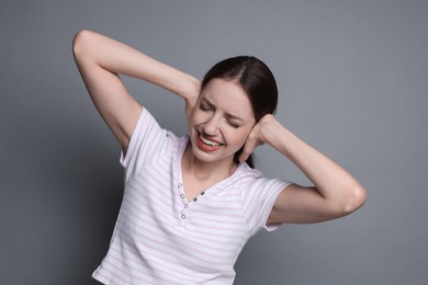 Woman covering her ears on grey background