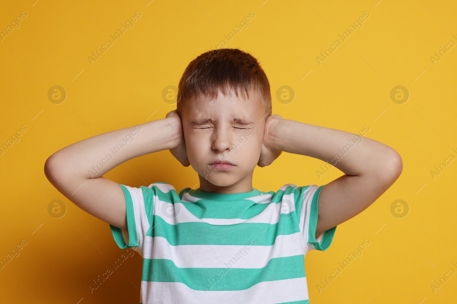 Photo of Little boy covering his ears on orange background