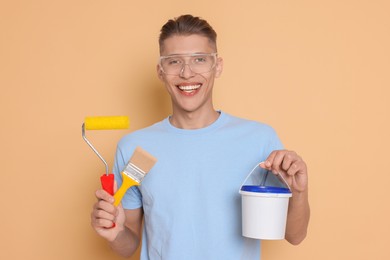 Photo of Portrait of young decorator with different tools on beige background