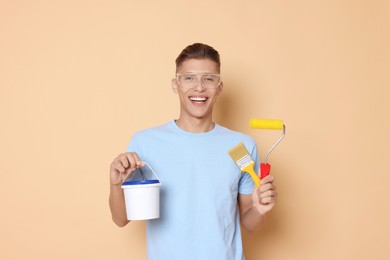 Photo of Portrait of young decorator with different tools on beige background