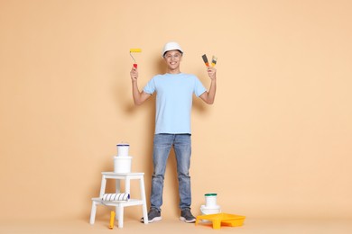 Photo of Young decorator with different tools on beige background