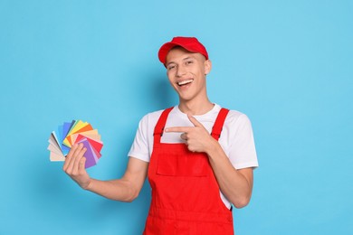 Photo of Portrait of young decorator with color palettes on light blue background