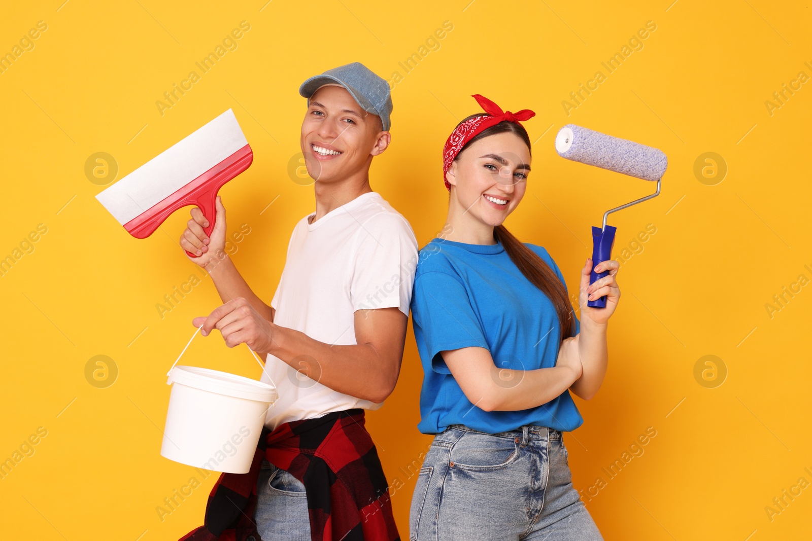 Photo of Professional decorator. Man and woman with different tools on orange background