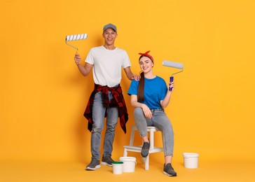 Photo of Professional decorator. Man and woman with different tools on orange background