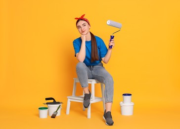 Photo of Young decorator with different tools on orange background