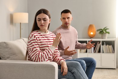 Photo of Tired woman stopping her husband at home. Relationship problems