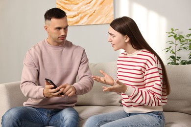 Photo of Husband showing smartphone with proofs to his unfaithful wife at home