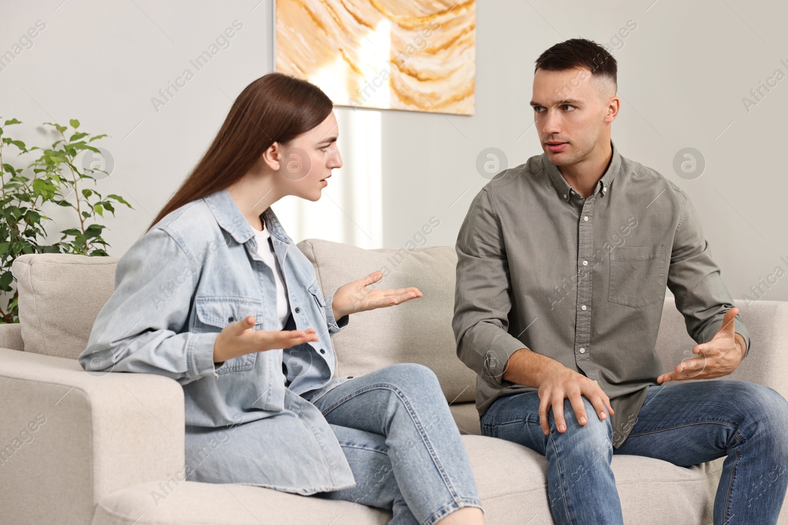 Photo of Young couple arguing on sofa at home