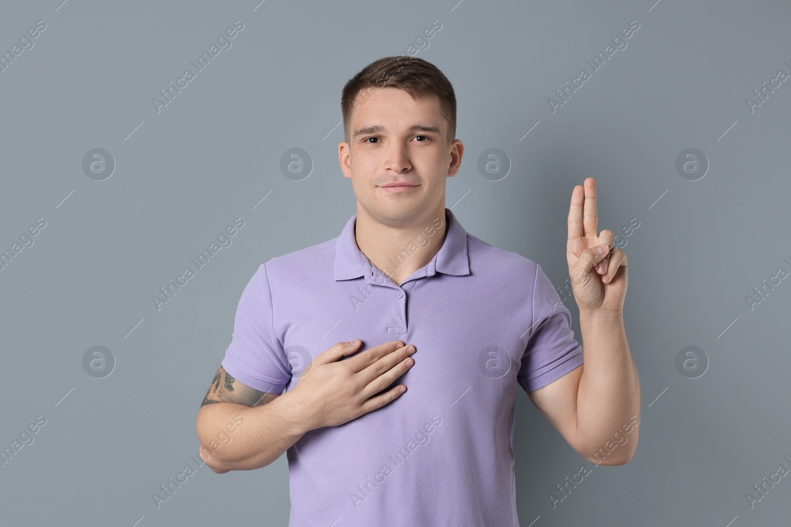 Photo of Man showing oath gesture on grey background. Making promise