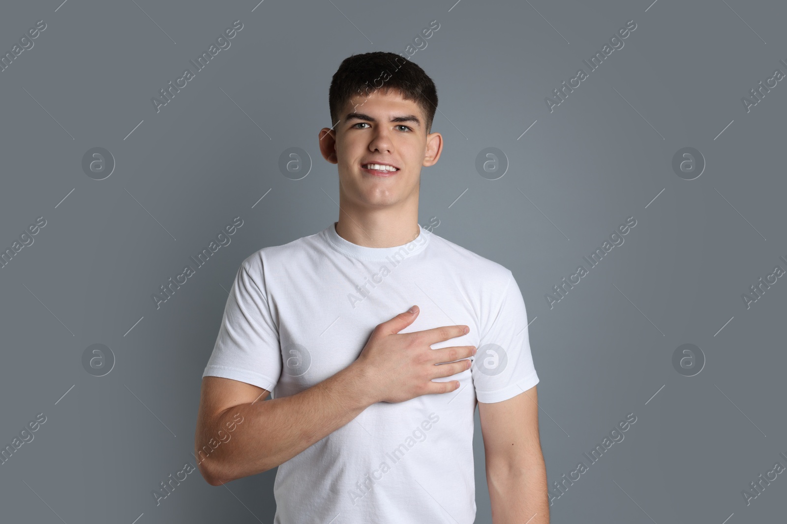 Photo of Man making promise on grey background. Oath gesture