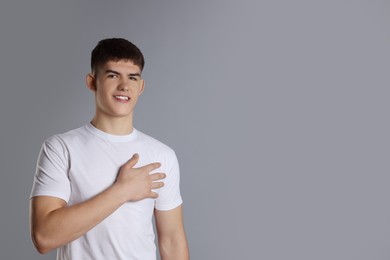 Photo of Man making promise on grey background, space for text. Oath gesture