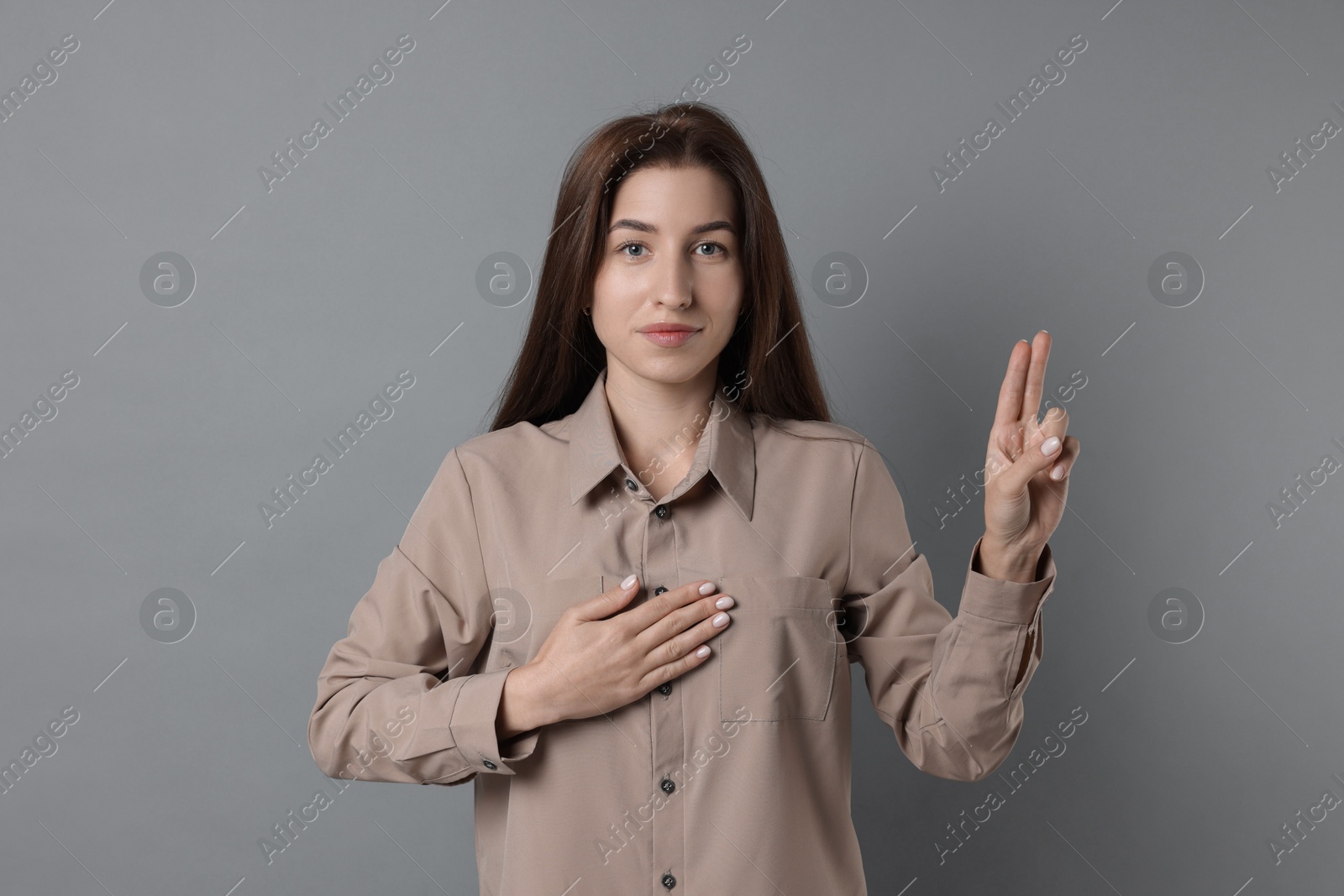 Photo of Woman showing oath gesture on grey background. Making promise