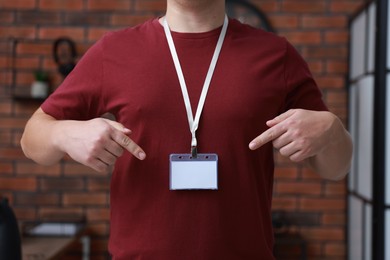 Photo of Man with blank badge in office, closeup