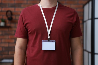 Photo of Man with blank badge in office, closeup