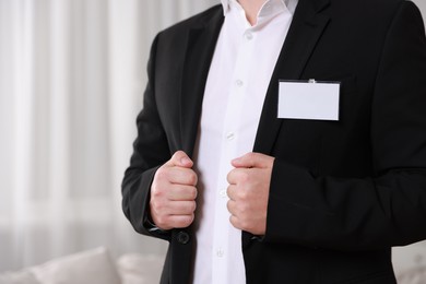 Photo of Man with blank badge indoors, closeup. Space for text