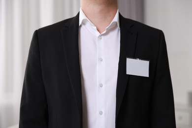 Photo of Man with blank badge indoors, closeup view