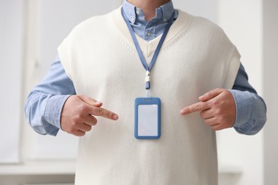 Photo of Man pointing at blank badge indoors, closeup