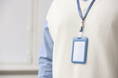 Photo of Man with blank badge indoors, closeup. Space for text