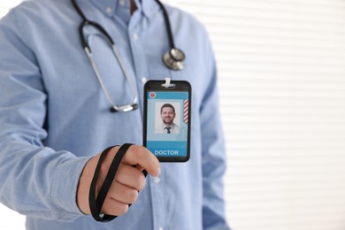 Doctor with badge in hospital, closeup. Space for text