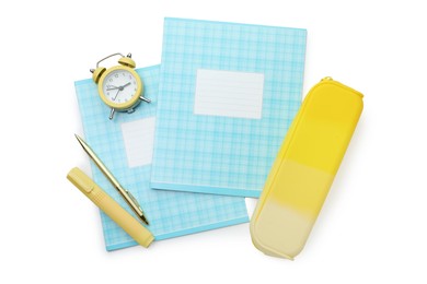 Photo of Copybooks, pencil case, pens and alarm clock on white background, top view