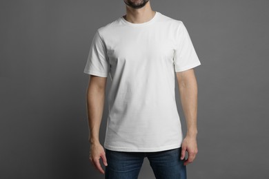 Photo of Man in blank white t-shirt on grey background, closeup. Mockup for design