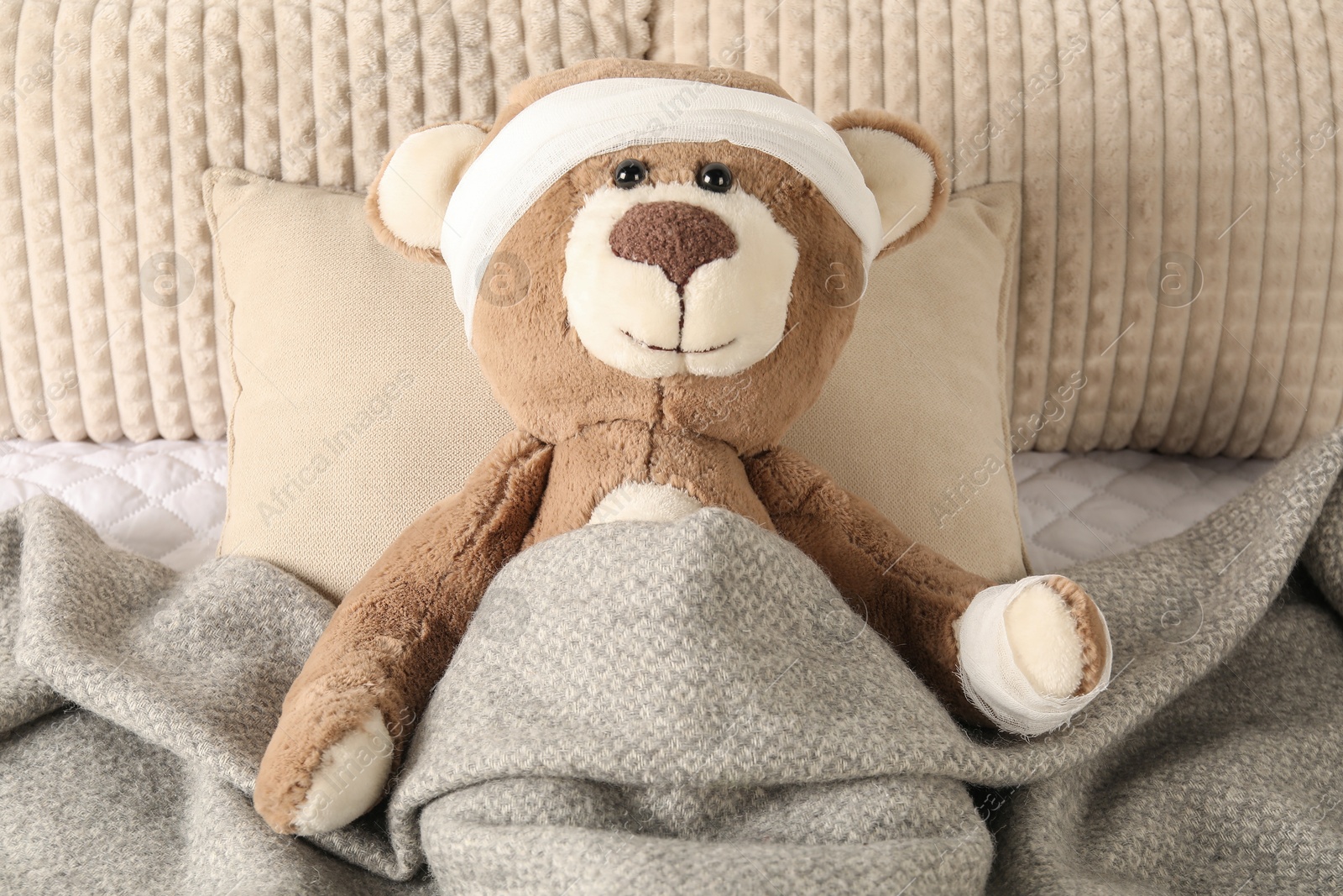 Photo of Cute teddy bear with bandages on bed, top view