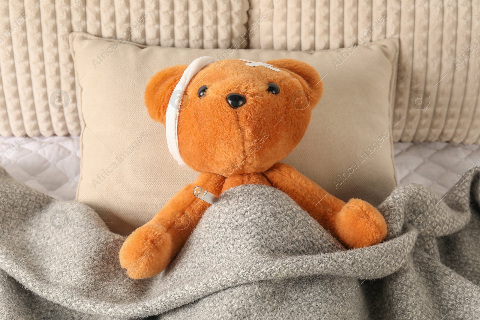 Photo of Cute teddy bear with bandage, adhesive medical plasters and thermometer on bed, top view