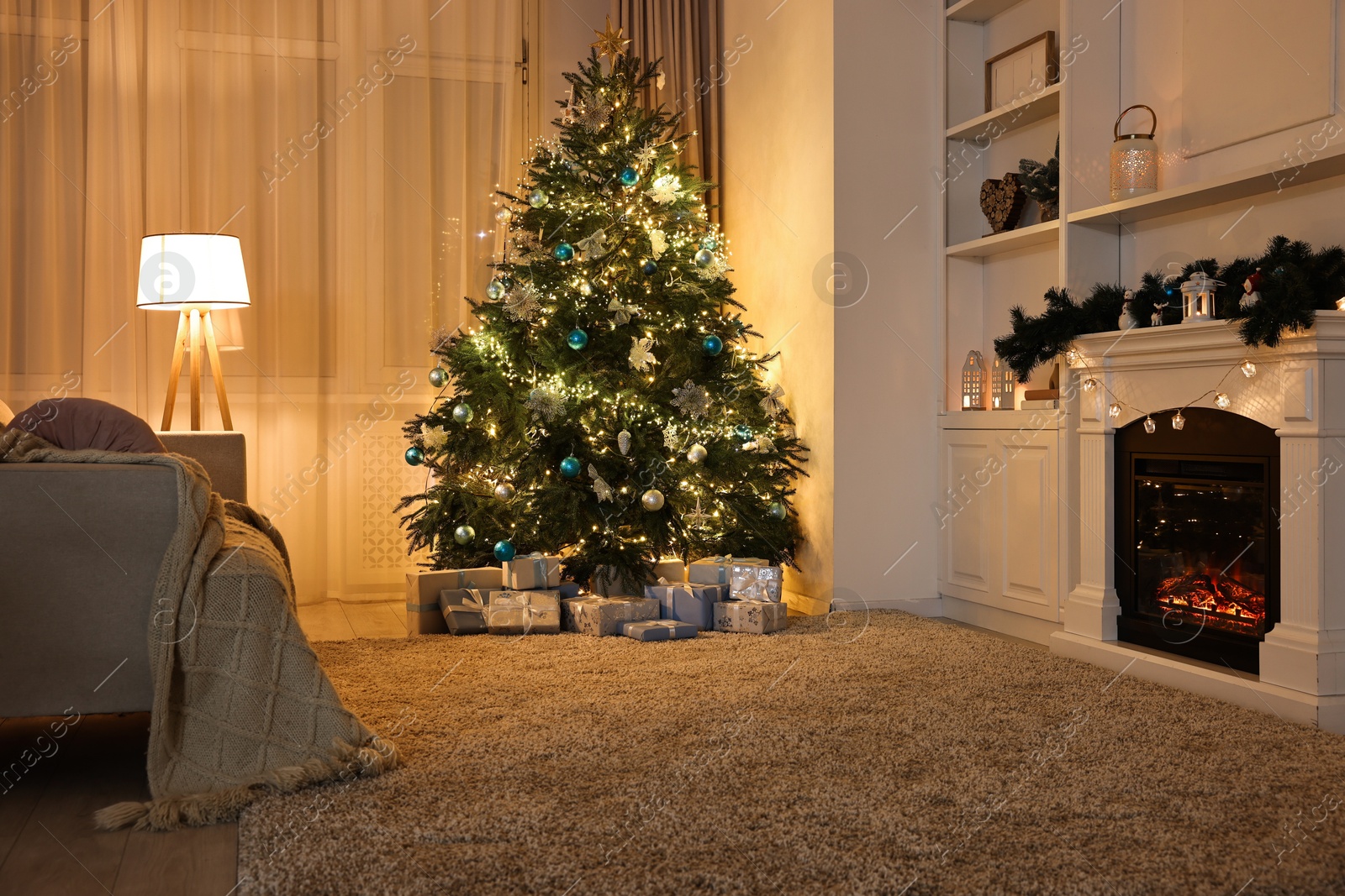 Photo of Christmas tree and decorated fireplace in room. Festive interior