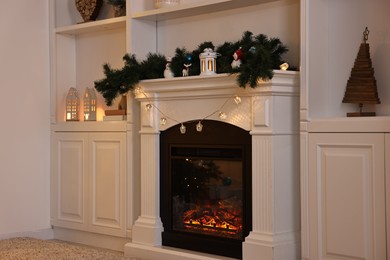 Photo of Fireplace with garland and other Christmas decor indoors