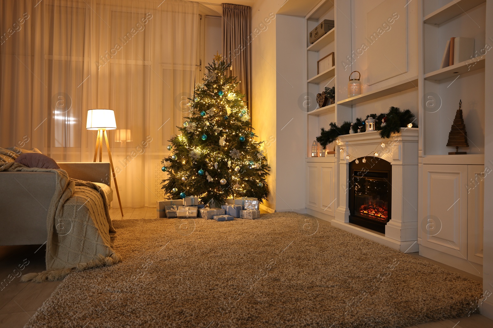 Photo of Christmas tree and decorated fireplace in room. Festive interior