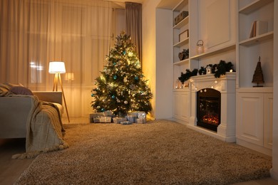 Photo of Christmas tree and decorated fireplace in room. Festive interior