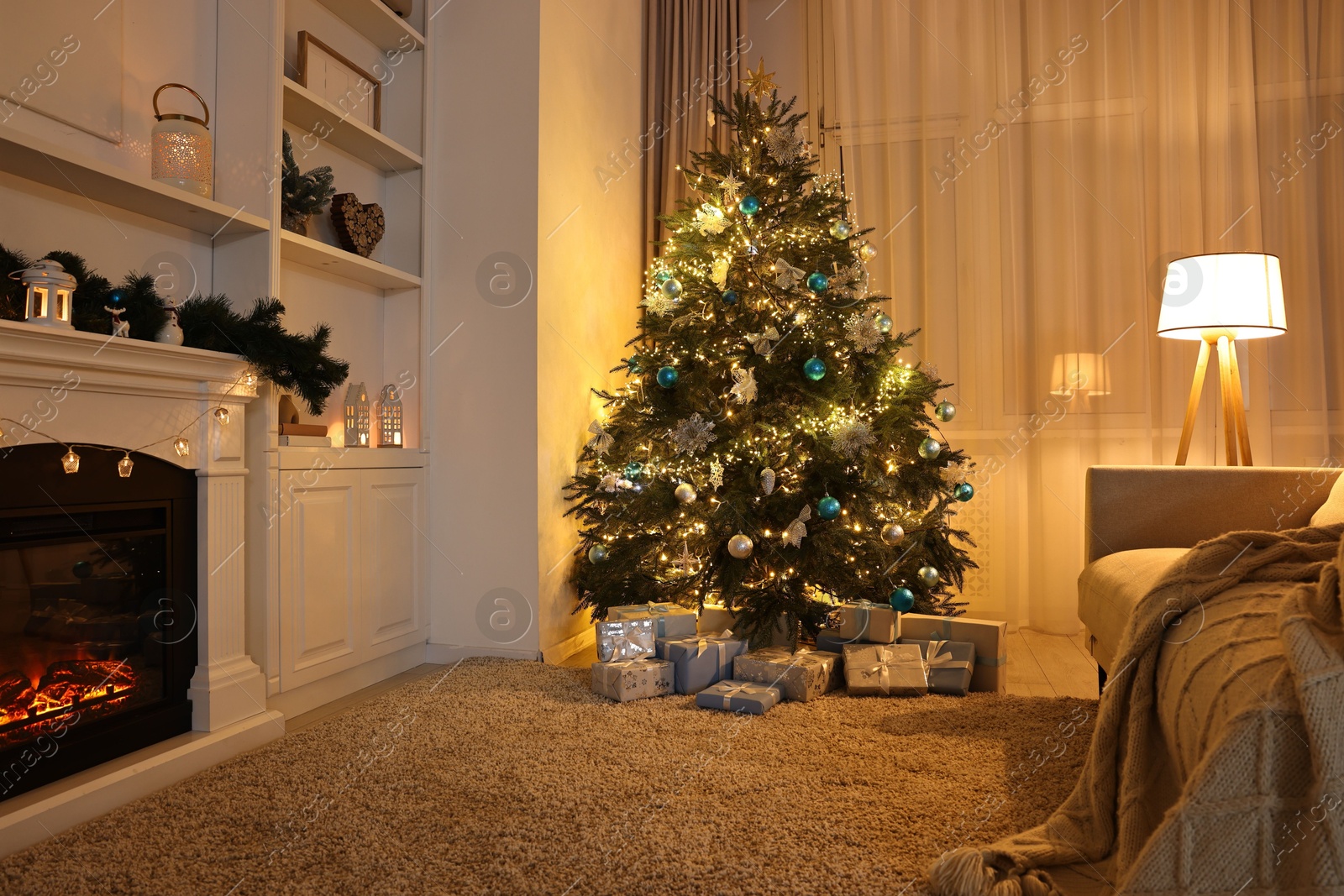 Photo of Christmas tree and decorated fireplace in room. Festive interior