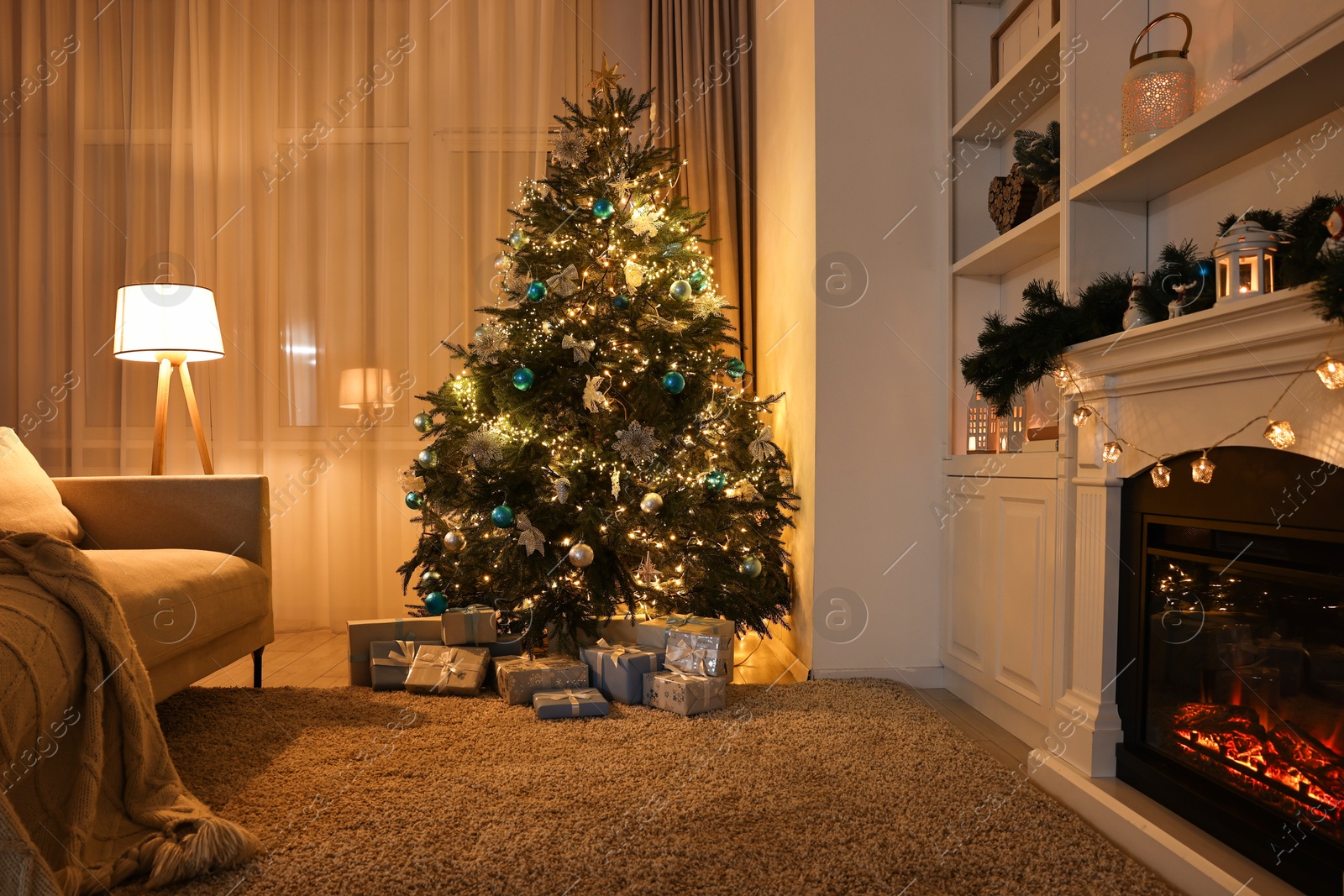 Photo of Christmas tree and decorated fireplace in room. Festive interior