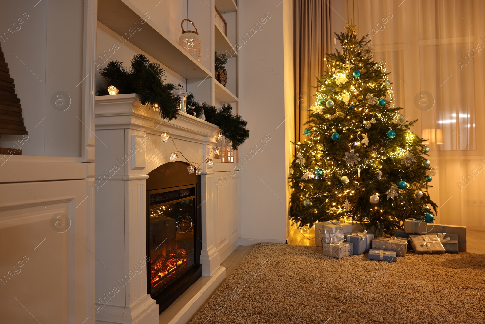 Photo of Christmas tree and decorated fireplace in room. Festive interior