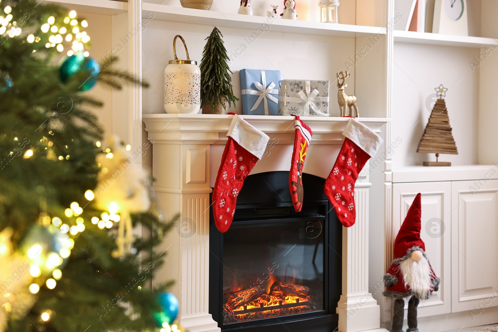 Photo of Fireplace with stockings and Christmas tree indoors