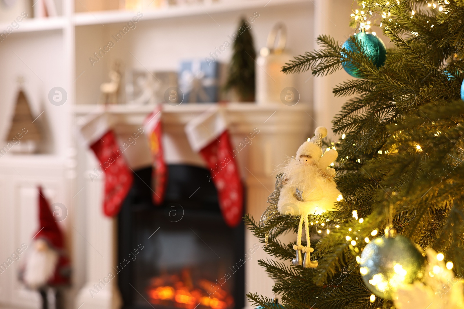 Photo of Christmas tree with baubles near fireplace indoors, closeup