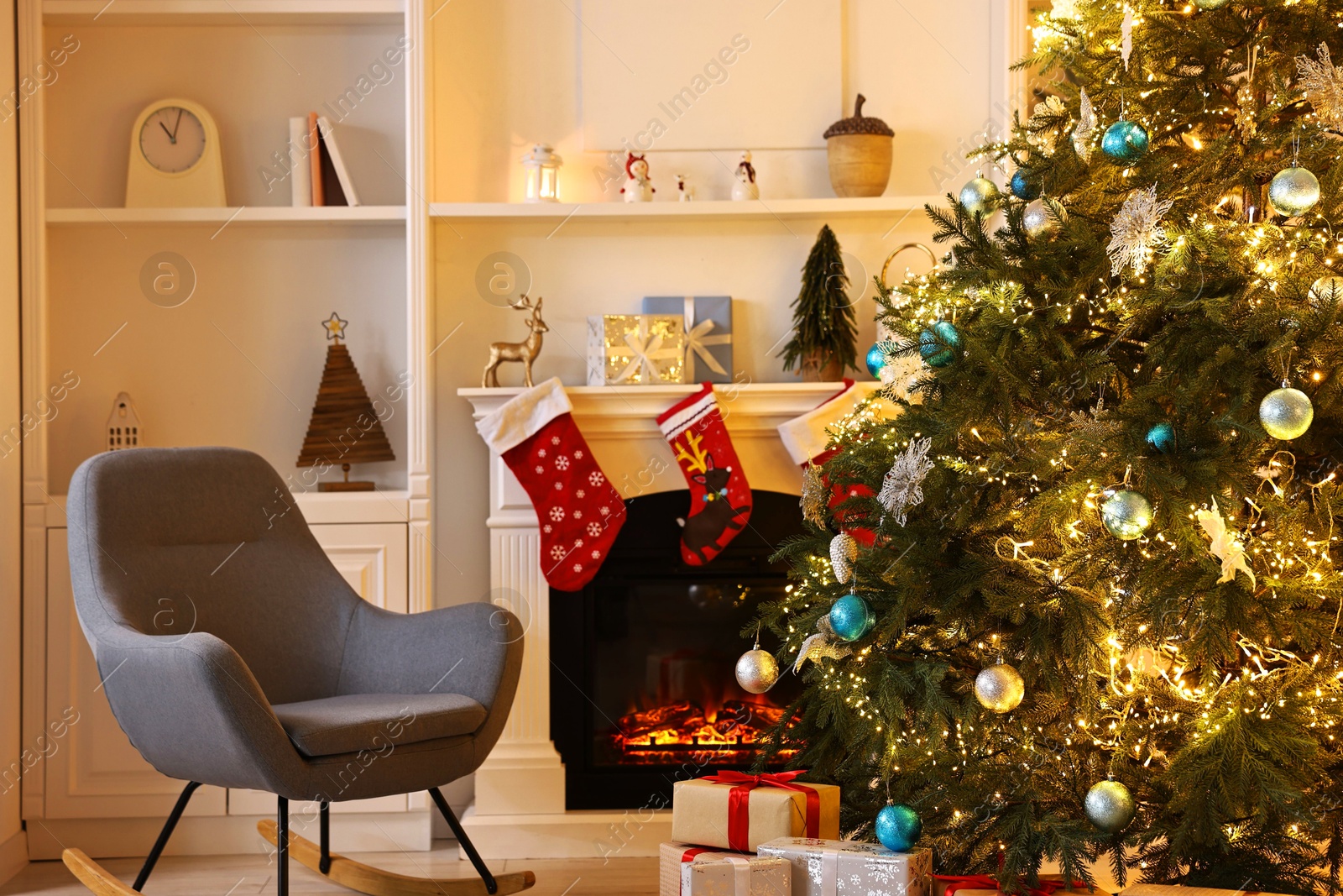 Photo of Christmas tree and rocking chair near decorated fireplace in room. Festive interior